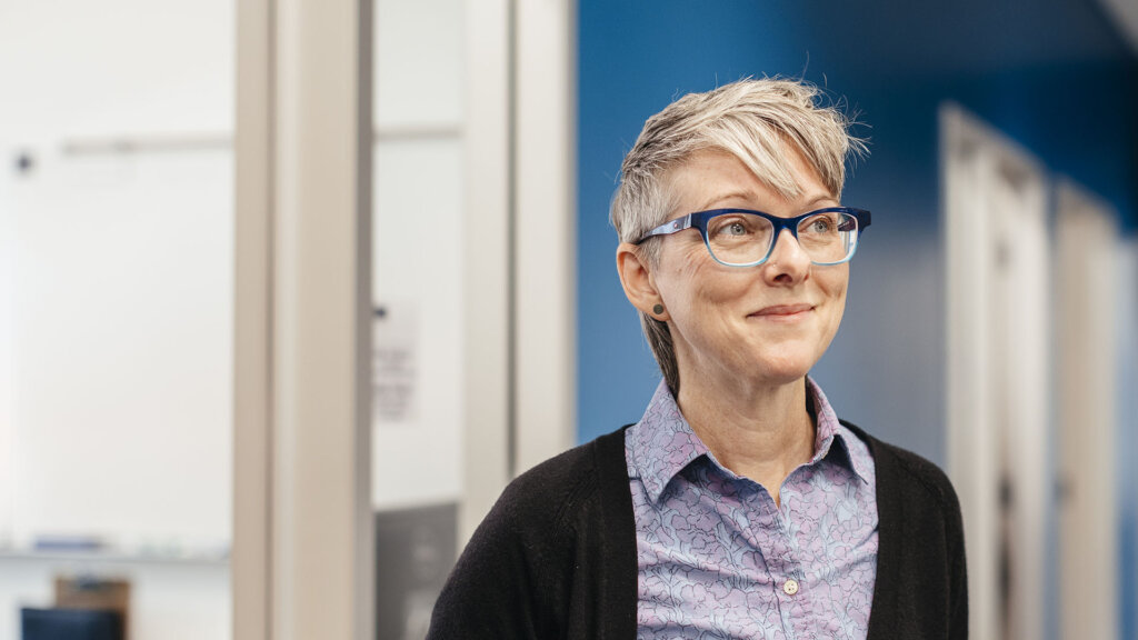 Smiling woman with grey hair and glasses in an academic setting