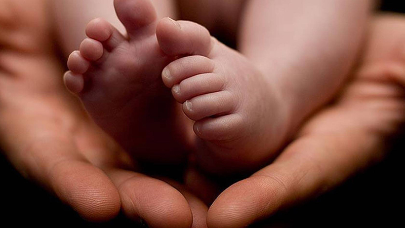 Adult person holding baby's feet