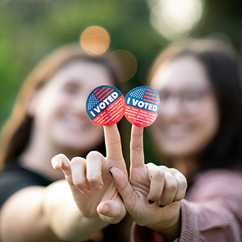 Portrait of two women holding out their hands together with the I voted stickers attached to their fingers