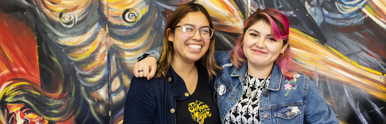 Students embracing in front of mural at the UC Riverside Chicano/a community center