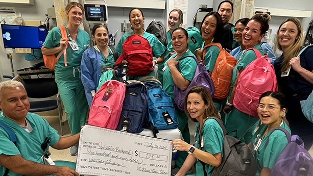 UC Davis Health staff pose with backpacks and a commemorative check