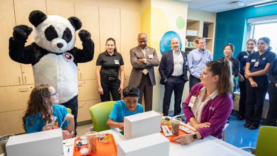 Panda Express mascot with children and UC Davis Health leadership and staff at the UC Davis Panda Cares Center of Hope