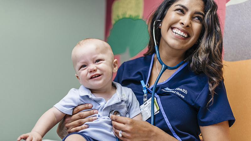 Smiling nurse holding baby