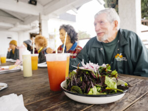 group of older people eating together at outdoor table