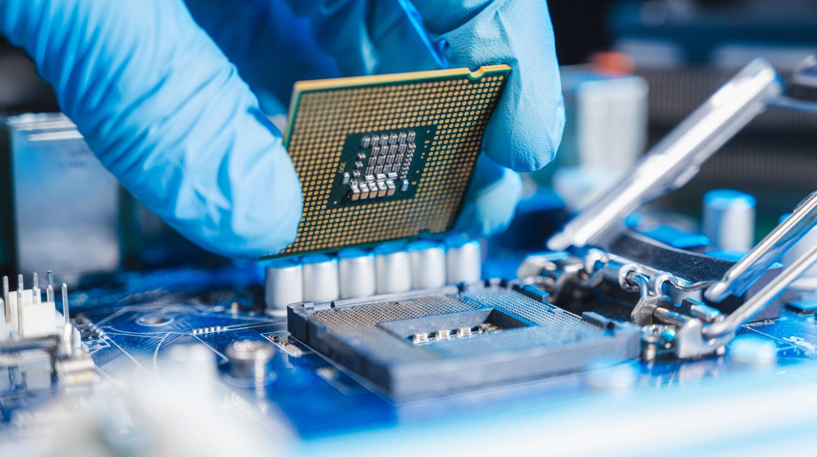 A person's gloved hand works on a microchip