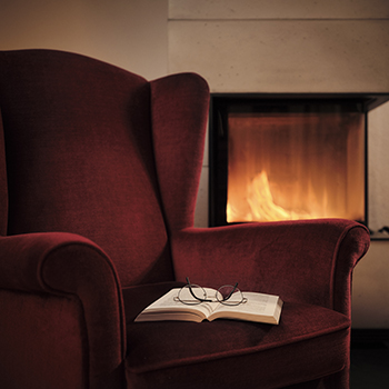 Cozy chair with book in front of a fire