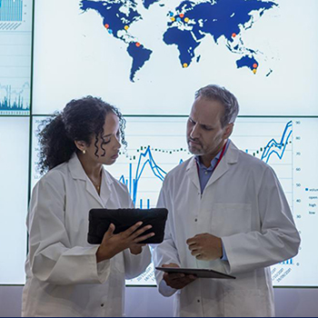 Scientists working together in front of projected data graphs and maps