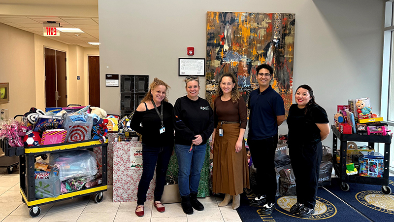 Anna Thron and Sheri Alley from Walden Family Services pose with UCPath staff and donated gifts.