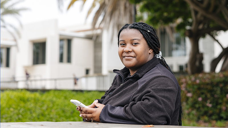 Woman sitting outside on campus looking at her phone