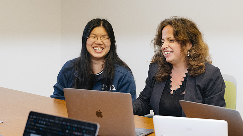 Women working side by side on laptops at a table