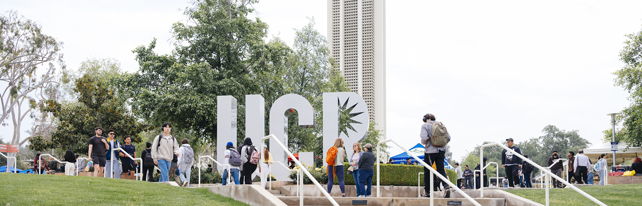 UC Riverside students walking past UCR sign
