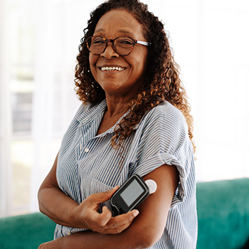 Diabetic woman using a flash glucose monitor to measure her blood sugar levels with a simple scan, allowing her to adjust her diet and medication as needed for optimal health and wellness.