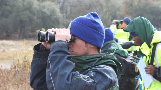 Student looks across a field with binoculars
