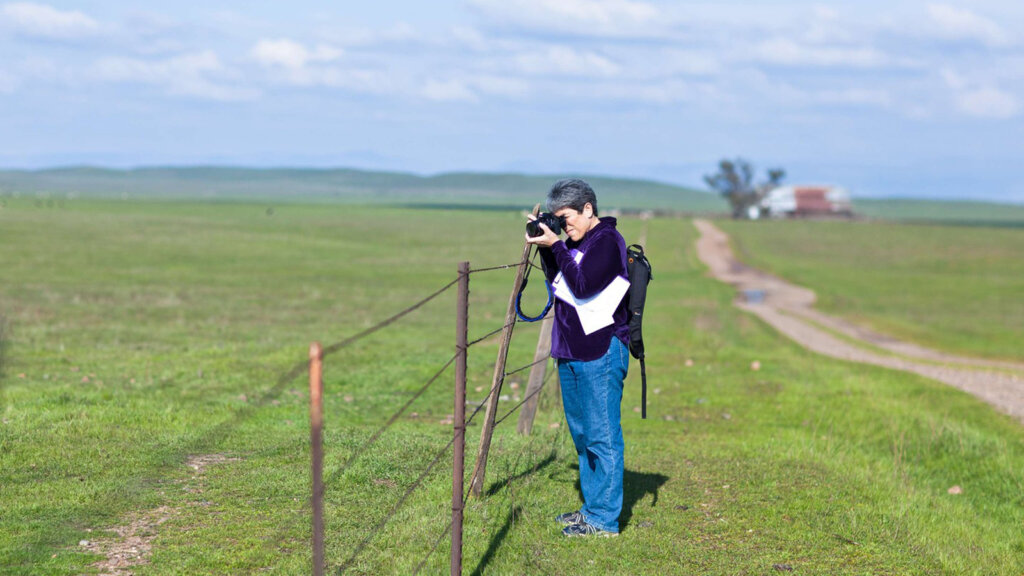 Veronica Adrover holding a camera in a field to photograph something