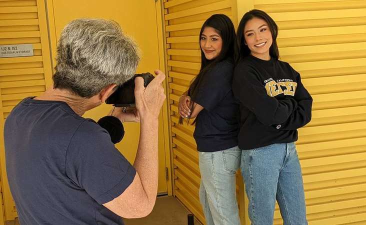 Two students standing back-to-back in front of a photographer