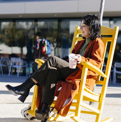 Smiling person sitting in colorful rocking chair on a sunny day