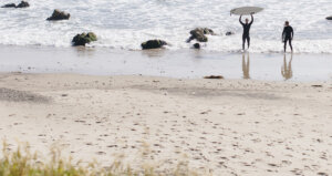 Two surfers in the distance on the beach