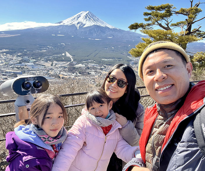 Brian, his wife, and daughters posing on an overlook of a mountaintop
