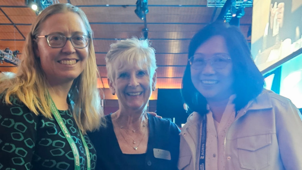Three women standing together with conference badges