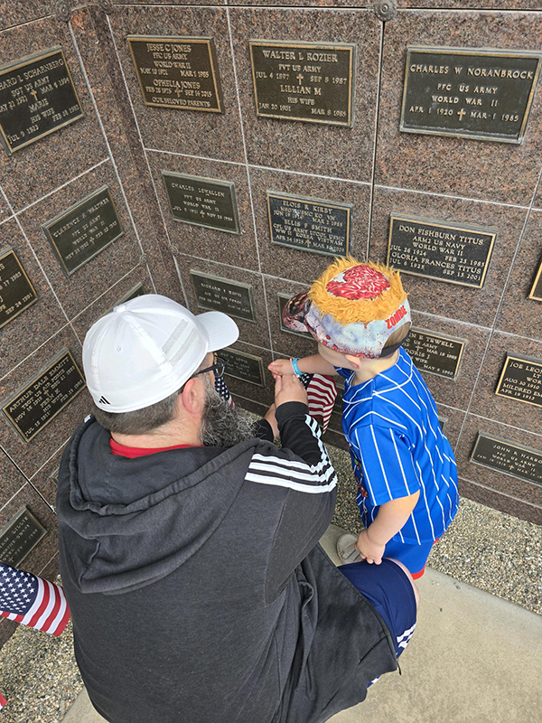 Man holding child in front walled gravesites