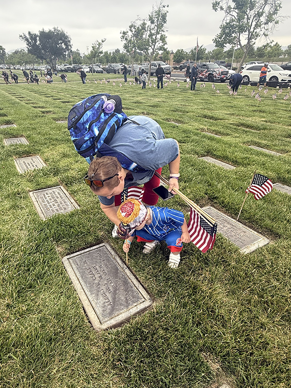 Mother and child placing flag on grave