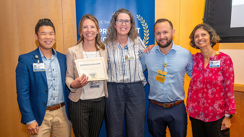 Group of smiling people holding a certificate