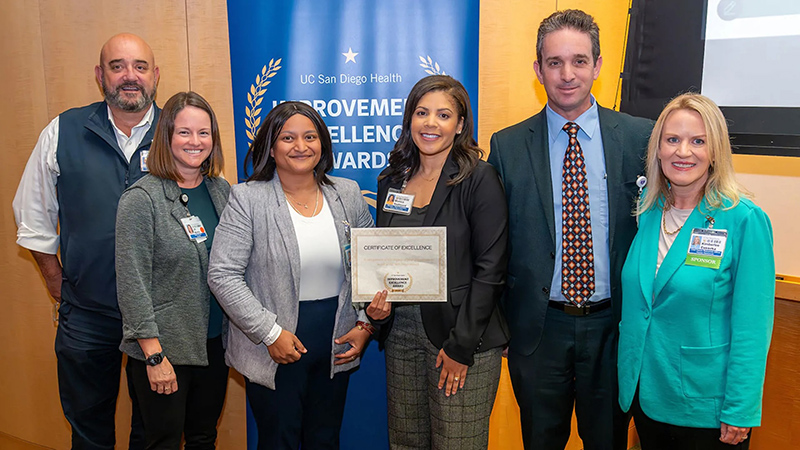 Group of smiling people holding a certificate
