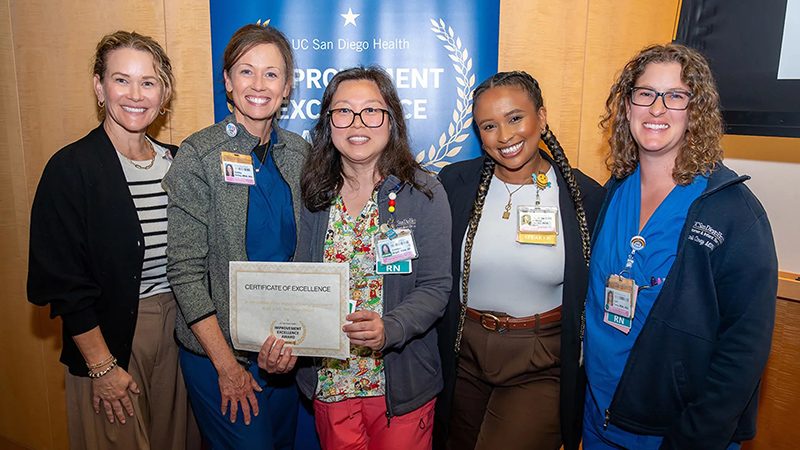 Group of smiling people holding a certificate
