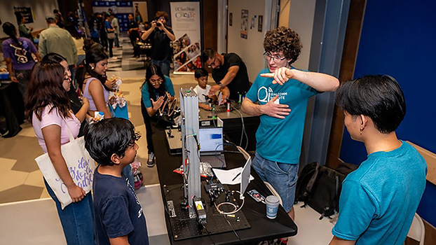 Students explain the science of gravity at a display table