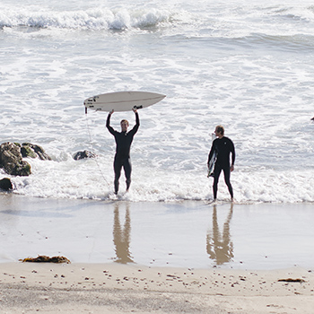 Two surfers in the distance on the beach