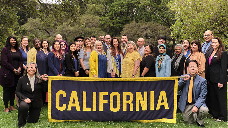 Group of people holding a large banner with the word “California.”