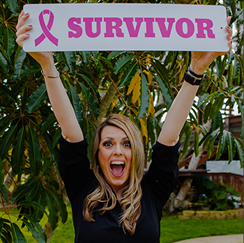 Michelle holding up a breast cancer survivor sign