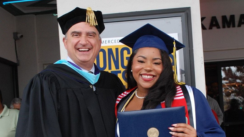 Smiling man and woman in academic regalia