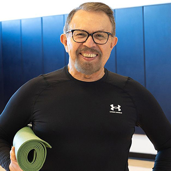 Arturo holding a yoga mat and smiling