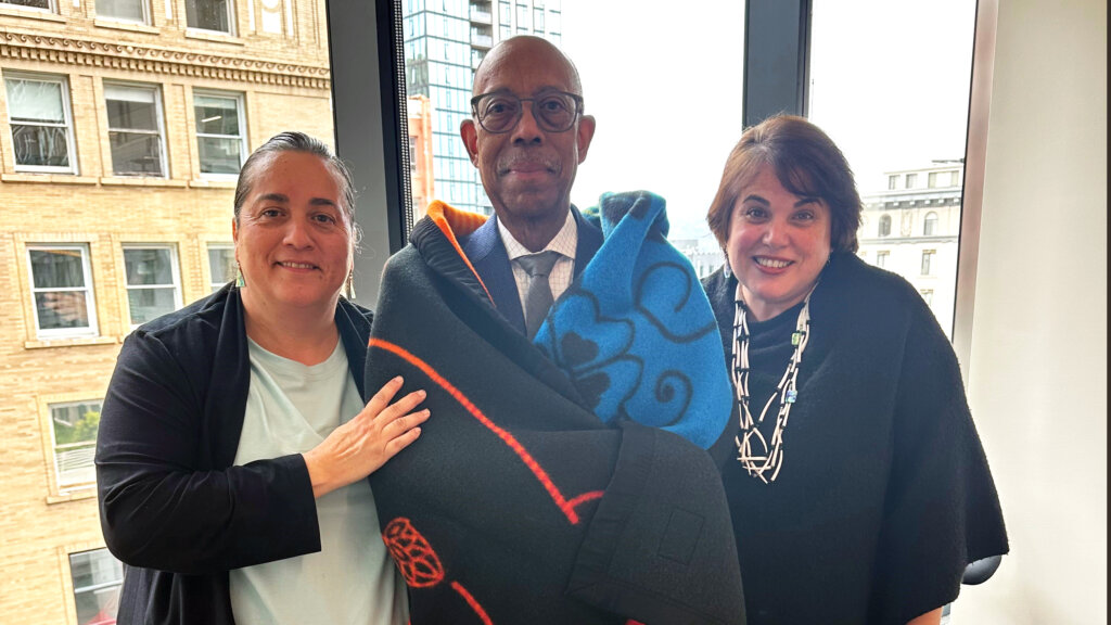 President Drake wrapped in a blanket by two women