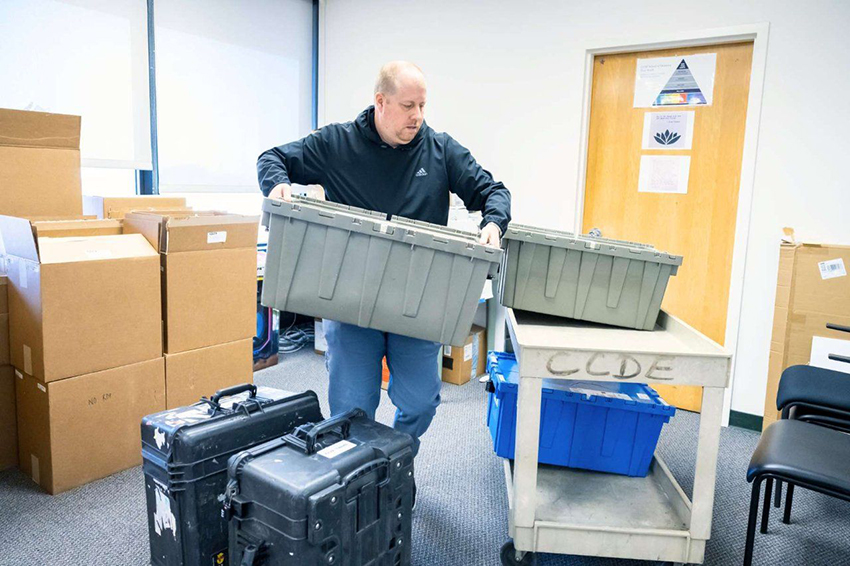 David moving large crates with exams