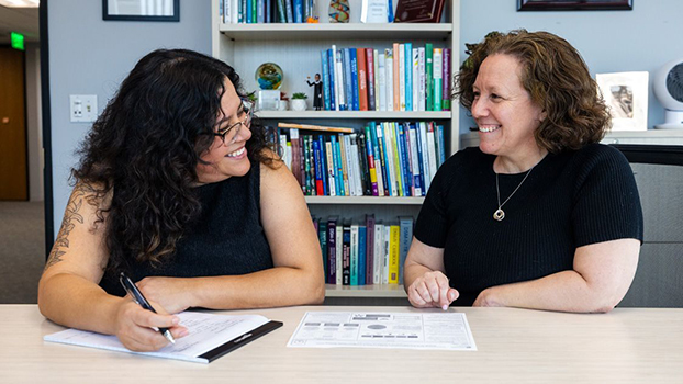 Two smiling women talking at a table