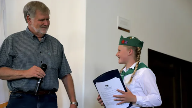 Man holding a mic and talking to a girl wearing a 4-H beret