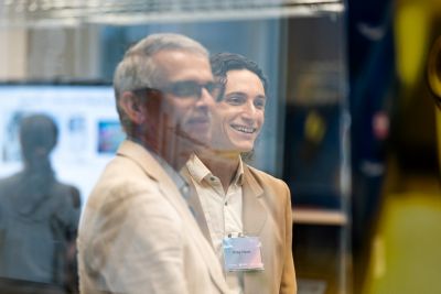 Two men standing together in a glass-walled room