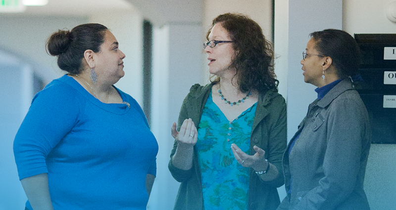 Three staff members talking.