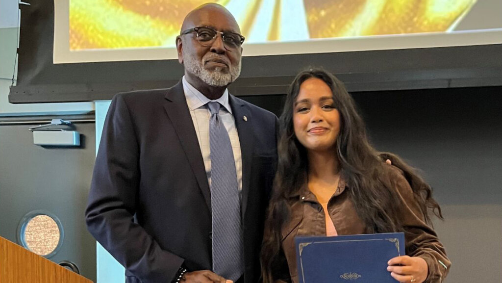 Charles with his arm around a student receiving a certificate