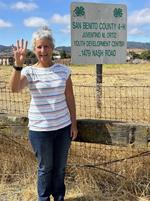 Emily standing by a fence, waving