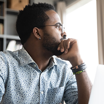 Thoughtful serious african professional business man sit with laptop thinking of difficult project challenge looking for problem solution searching creative ideas lost in thoughts at home office desk