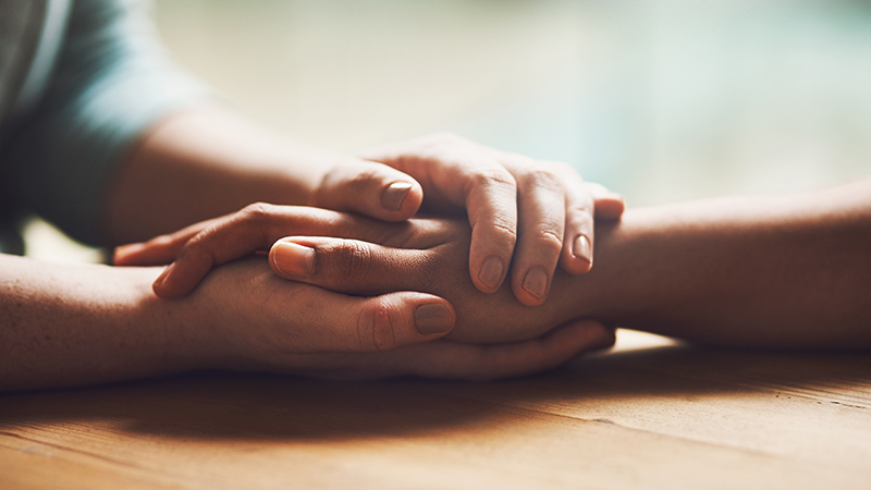 Two people holding hands in comfort