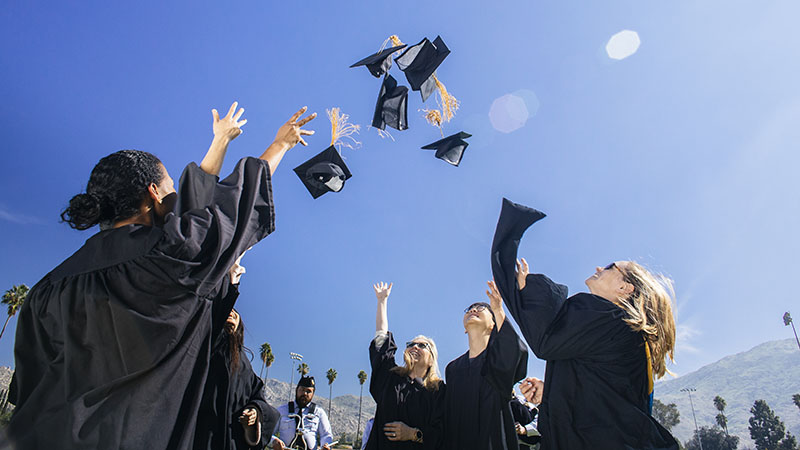 Students in graduation attire throwing their hats into the air