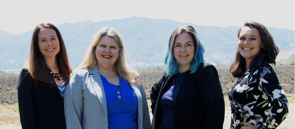 Four women standing in front of a CA landscape