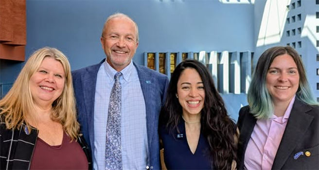 Four smiling people standing together in business attire