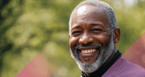 Smiling person with graying hair and beard smiling outside
