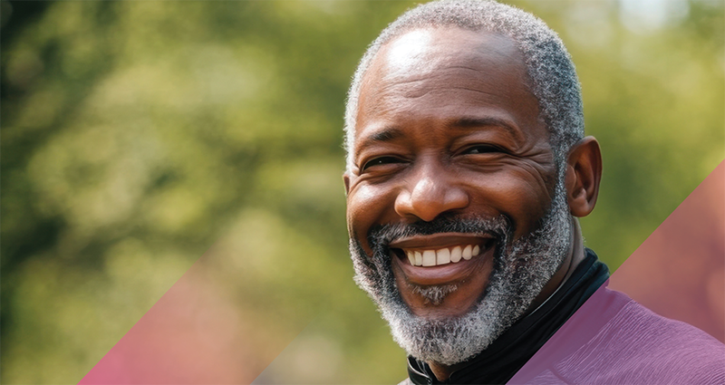 Smiling person with graying hair and beard smiling outside