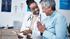 Black woman doctor and elderly patient with good news